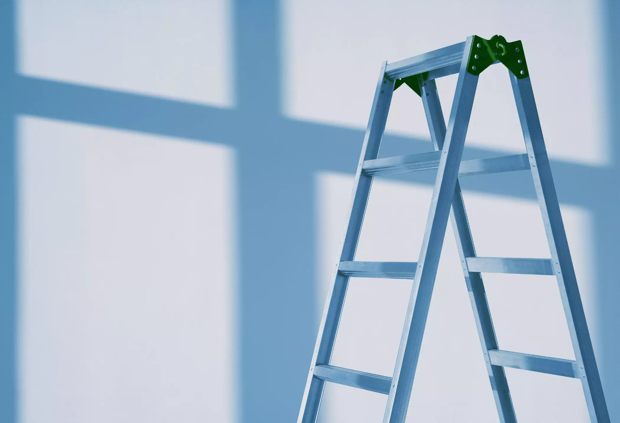 A metal stepladder standing open against a light blue wall with window shadows.